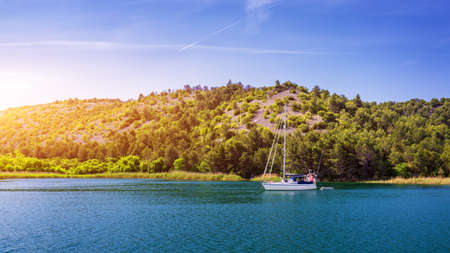 Sailboat in the sea in the evening sunlight with mountains background, luxury summer adventure, active vacation in Mediterranean sea, Croatia. Sailing ship luxury yacht with white sails in the Sea.の写真素材