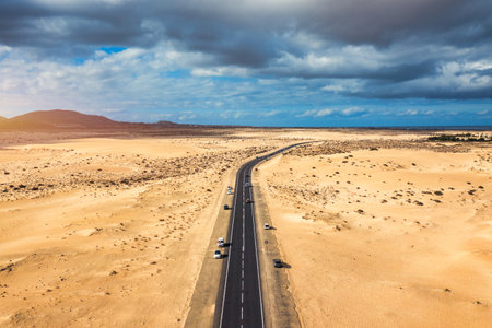 Fuerteventura, Corralejo sand dunes nature park. Beautiful Aerial Shot. Canary Islands, Spain. Aerial view of an empty road through the dunes at the sunset. Fuerteventura, Canary Islands, Spain.のeditorial素材