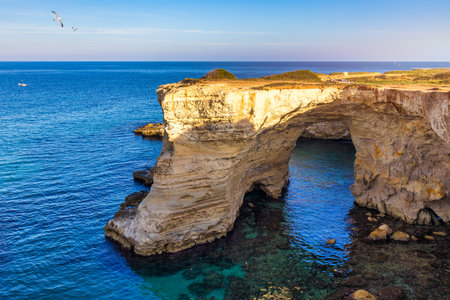 Stunning seascape with cliffs rocky arch and stacks (Faraglioni) at Torre Sant Andrea, Salento coast, Puglia region, Italy. Beautiful cliffs and sea stacks of Sant'Andrea, Salento, Apulia, Italyの写真素材