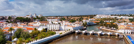 View on historic town of Tavira with Roman bridge over River Gilao, Algarve, Portugal. Cityscape of the Tavira old town with Clock tower, St Marys church, Algarve region, Portugal.の写真素材