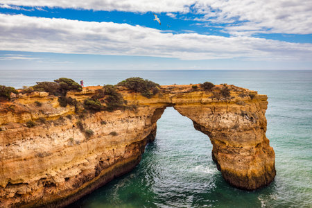Natural arch above ocean, Arco de Albandeira, Algarve, Portugal. Stone arch at Praia de Albandeira, Lagoa, Algarve, Portugal. View of the natural arch Arco da Albandeira in the Algarve, Portugal.の写真素材