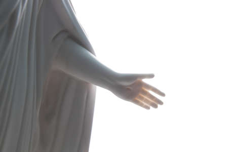 Close up of the crucified hand of Jesus Christ on marble statue with a white backgroundの写真素材