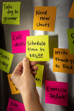 Hand Holding Schedule Time to Relax Sticky Note Memo to Fridge Door Full of Colorful Reminders