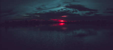 A colorful sunset with cloudy a sky reflecting in the surface of a pondの写真素材