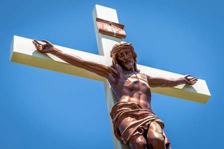Gold colored statue at a cemetery of Jesus Christ hanging on the crossの写真素材