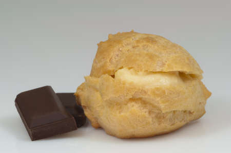 single cream puff and pieces of chocolate and white background - DSC0716の写真素材