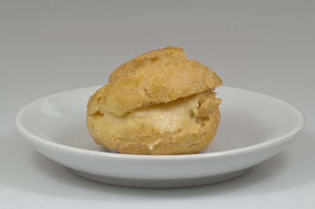 single cream puff on the coffee-cup plate with white background - DSC0691の写真素材