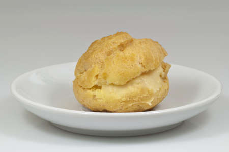 single cream puff on the coffee-cup plate with white background - DSC0693の写真素材