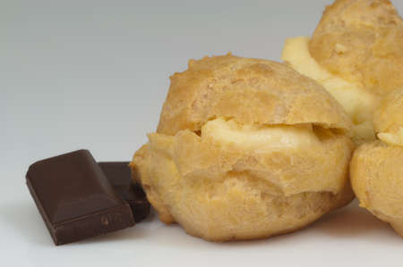 three cream puffs and pieces of chocolate and white background - DSC0720の写真素材