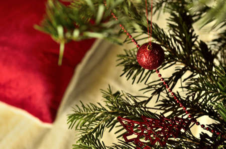 Decorated Christmas Tree with Red Ornaments and a Fluffy Red Pillow near the Tree.