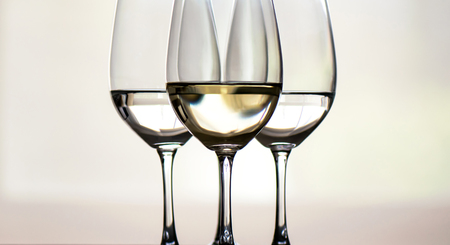 Four glasses of white wine, arranged symmetrically, focus on the middle oneの写真素材
