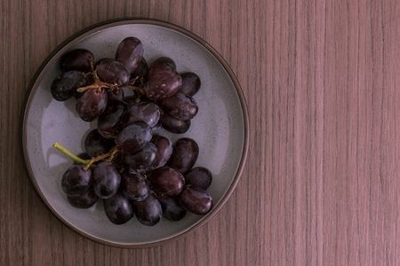 A bowl of red grapes over wood backgroundの写真素材
