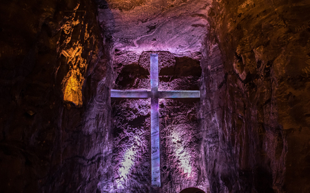 Beautiful christian cross carved in the rock and lighted by colored lightsの写真素材