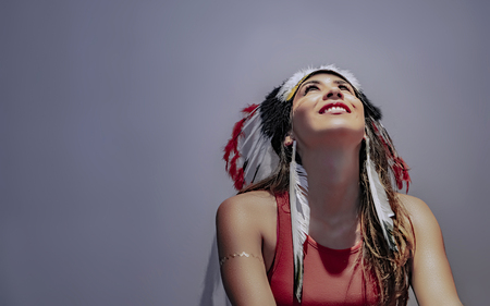Portrait of a latin model with a feathered headdress with lights and shadows accentuated on her face
