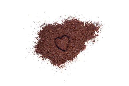 Pile of coffee grounds with a heart shaped indent isolated on white backgroundの写真素材