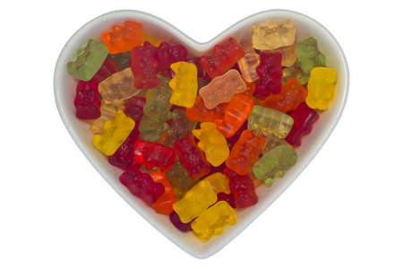 Heart-shaped bowl filled with gummy bears, isolated on white backgroundの写真素材