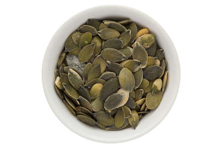 Pumpkin seeds in white bowl, isolated on white backgroundの写真素材