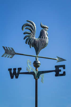 Weather vane showing direction of wind against clear blue sky, verticalの写真素材