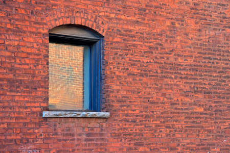 An arched window opening in a vintage brick wall.