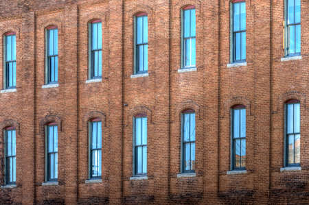 A large number of wooden sash windows in an old industrial brick building