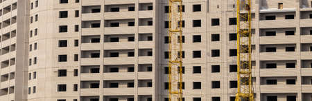 Construction site. Unfinished apartment building made of white bricks. Special yellow industrial...