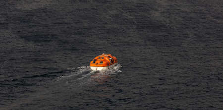 View of a single orange life boat with some seamen inside sailing at sea. Caribbean sea.の写真素材