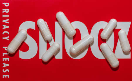 Close-up shot of white pills on red snoozing sign with soft focus background. Background with Snooz and Privacy please words on itの写真素材