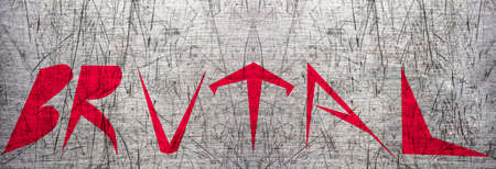 Word "Brutal" painted in red on scratched metal surface. Sharp shaped letters. Isolated. Metal background.の写真素材