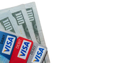 Miami, Florida - May 29, 2020: Hundred dollar bills and visa debit cards on top of them. White...