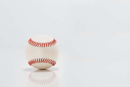 Professional baseball on white background. Isolated and reflecting in the surface below it.の写真素材