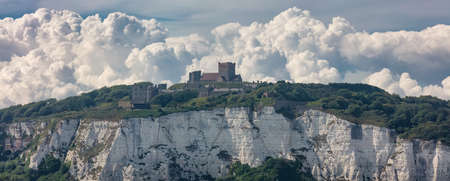 Panoramic shot of the White Cliffs of Dover and a castle on top of the cliff. Beautiful fluffy...