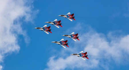 Barnaul, Russia - September 18, 2020: A low angle shot of Strizhi MiG-29 fighter jet squadron performing stunts during an aeroshow. Blue cloudy sky as a background.のeditorial素材