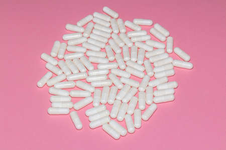 High angle shot of white pills on pink background. Healthcare, medical and pharmaceutical concept.
