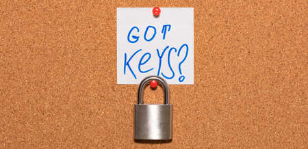 Closed padlock hanging on an empty notice board in business office. White sticky note above the...