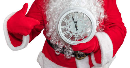 Santa Claus holding a white clock which shows five minutes to midnight and he is pointing at it. New year's eve concept. Isolated on white background.の写真素材