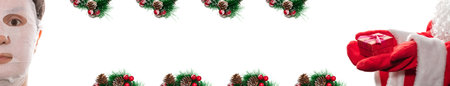 Santa Clauses' hands holding a red gift box. Pretty woman's face has a moisture mask on. Christmas pine twigs surround copy space. Beauty salon ad, holidays offer concept. Isolated, white background.の写真素材