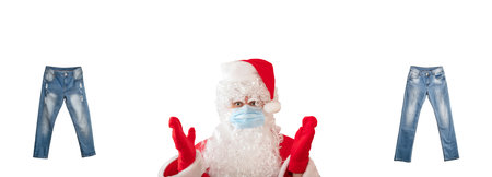 Santa Claus pointing at two pairs of light blue jeans isolated on white background. Jeans have white faded spots and ripped holes. Banner size, copy space. Clothing, online store concepts.の写真素材