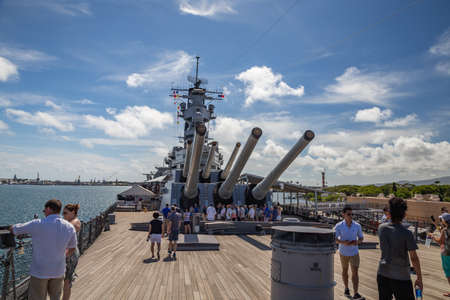 Pearl Harbor, Hawaii, USA - September 24, 2018: Huge cannons and deck of USS Missouri docked in Pearl Harbor. Deck full of tourists. Blue sky with white clouds as a background.のeditorial素材