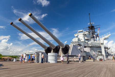 Pearl Harbor, Hawaii, USA - September 24, 2018: Huge cannons and deck of USS Missouri docked in Pearl Harbor. Deck full of tourists. Blue sky with white clouds as a background.のeditorial素材