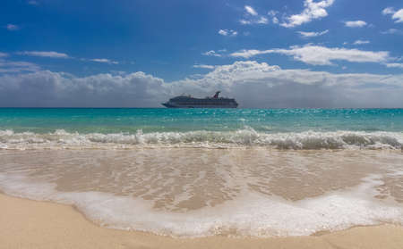 Half Moon Cay, Bahamas - February 19, 2020: Carnival Freedom anchoring by Half Moon Cay island. Gorgeous turquoise water splashing in the foreground. Cloudy blue sky in the background.のeditorial素材