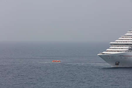 The Caribbean Sea - May 26, 2020: Aerial shot of Carnival Horizon anchored at sea and a single life boat approaching her. Gray, foggy sky in the background.のeditorial素材