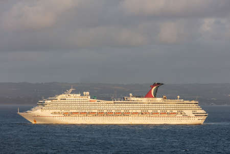 Saint Vincent and the Grenadines - May 11, 2020: Shot of Carnival Valor anchored at sea off the coast of Saint Vincent island. Cloudy sky and shoreline in the background.のeditorial素材