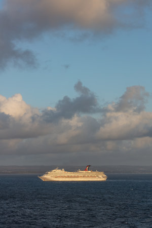Saint Vincent and the Grenadines - May 11, 2020: Shot of Carnival Valor anchored at sea off the coast of Saint Vincent island. Blue cloudy sky and shoreline in the background. Portrait size shot.のeditorial素材