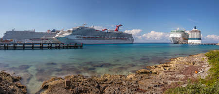 Cozumel, Mexico - December 31, 2019: Low angle panoramic shot of Carnival Freedom and other cruise ships docked in Cozumel. Gorgeous smooth turquoise water, rocky shore, wooden pier in the foreground.のeditorial素材