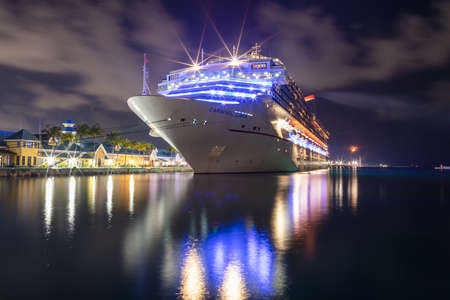 Nassau, Bahamas - June 8, 2019: Beautiful Carnival Liberty cruise ship docked at Prince George Wharf at night. Light reflections in the harbor water. Port lights, dark cloudy sky in the background.のeditorial素材