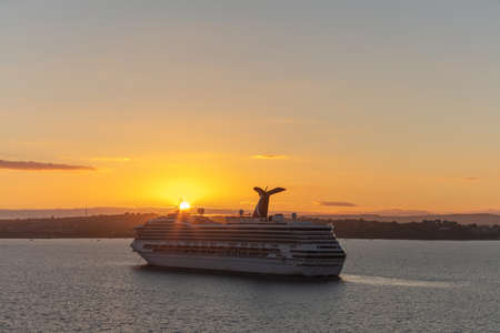 Portland, United Kingdom - July 1, 2020: Beautiful high angle shot of Carnival Valor anchored in the harbor at sunset. Gorgeous orange sky and sun setting down in the background.のeditorial素材