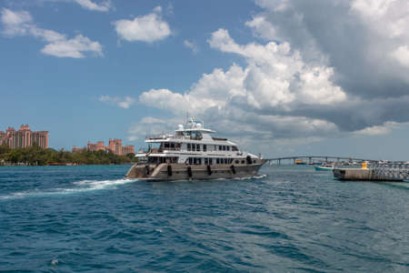 Nassau, Bahamas - May 14, 2019: Luxurious yacht Loon sailing in Nassau harbor.Turquoise water in the foreground. Atlantis resort, blue cloudy sky in the background.のeditorial素材