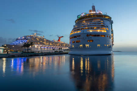 Nassau, Bahamas - July 13, 2019: Shot of Mariner of the Seas at Prince George Wharf at sunset. Blue hour. Gorgeous light reflections in the water in the foreground. Carnival Liberty in the background.のeditorial素材