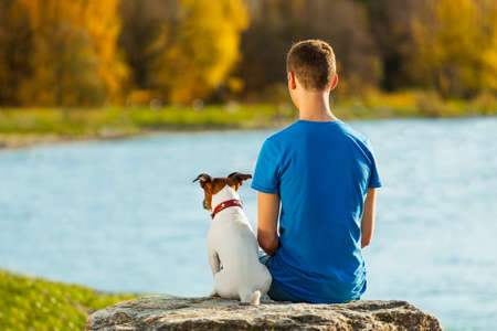boy and his dog sitting together enjoying the viewの写真素材