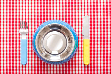 dog food bowl with knife and fork on tablecloth, empty and blankの写真素材